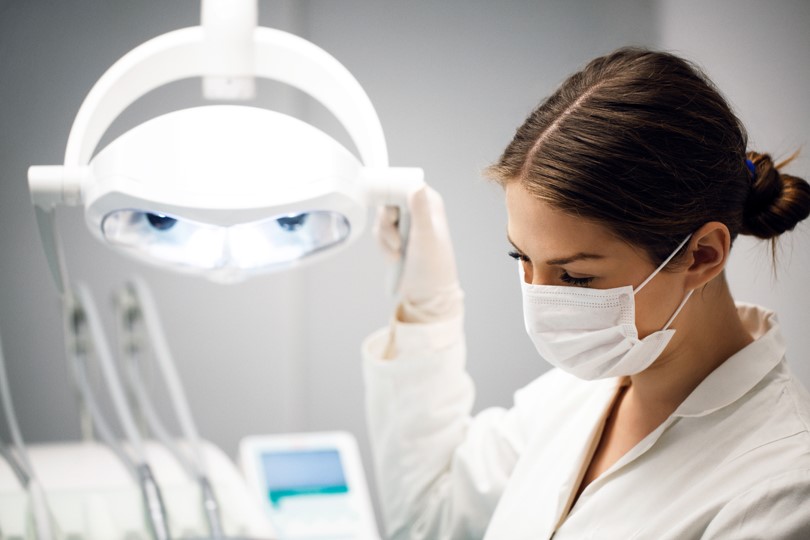 Female dentist looking at patient´s mouth using high density light.