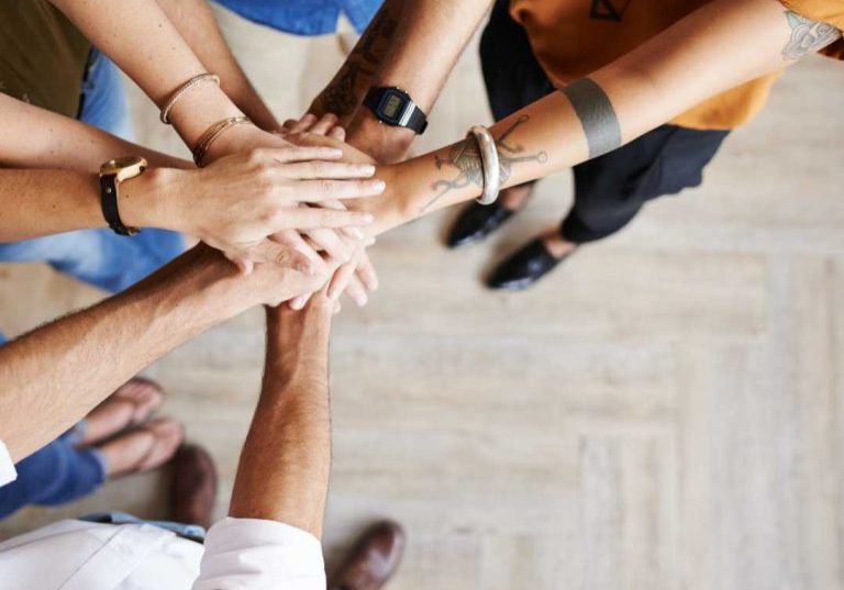 Circle of people with their hands in the middle